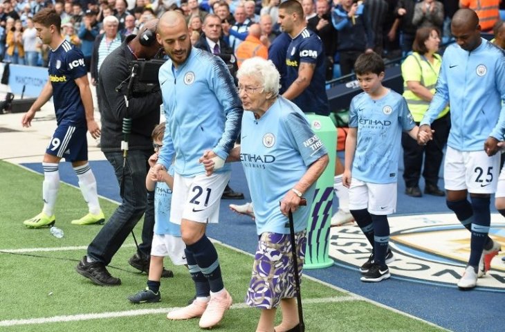 Gelandang Manchester City, David Silva menggandeng Vera Cohen sebagai maskot ketika pertandingan melawan Fulham (Paul Ellis/AFP)