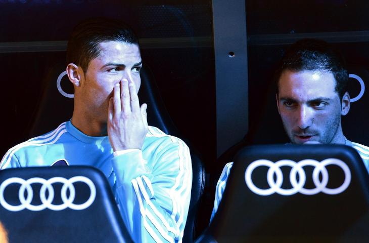 Cristiano Ronaldo (kiri) berbincang dengan Gonzalo Higuain di bangku cadangan saat masih berseragam Real Madrid dalam pertandingan melawan Barcelona di Stadion Santiago Bernabeu (2/3/2013) (AFP PHOTO/ JAVIER SORIANO)