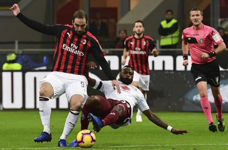 Penyerang AC Milan, Gonzalo Higuain mendapat tackle dari bek Torino, Nicolas Nkoulou pada 9 Desember 2018 (Miduel Medina/AFP)