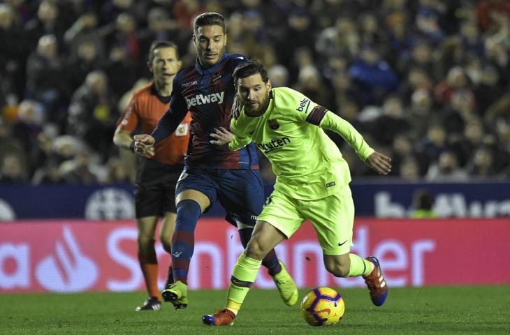 Pemain Levante, Ruben Rochina mencoba menghalau pemain Barcelona, Lionel Messi pada pertandingan pekan ke-16 La Liga Spanyol di Stadion Ciutat de Valencia (16/12/2018) (AFP)