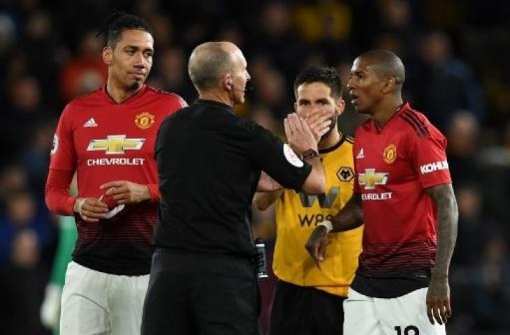 Wasit Mike Dean berbicara dengan Ashley Young pada laga melawan Wolverhampton Wanderers pada 2 April 2019 (Paul Ellis/AFP)