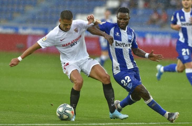 Penyerang Sevilla, Chicarito berebut bola dengan pemain Alaves, Mubarak Wakaso pada laga pekan keempat La Liga, Minggu (15/9/2019) malam. Pada laga itu Sevilla menang 1-0. [ANDER GILLENEA / AFP]