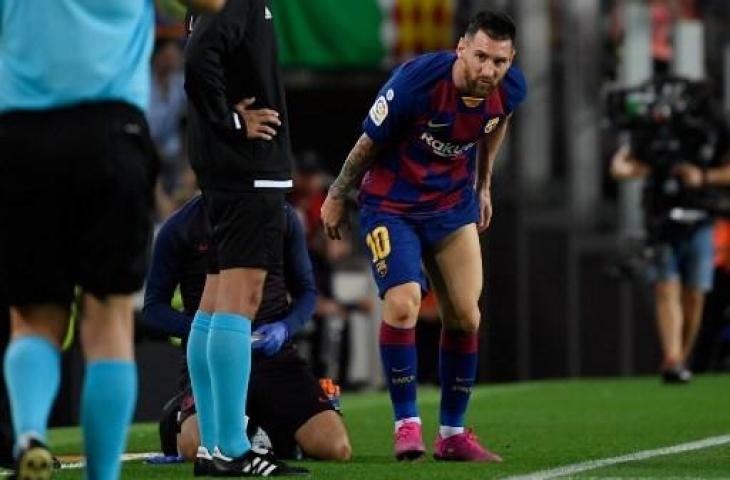 Lionel Messi nampak memegangi paha kirinya saat Barcelona menghadapi Villarreal. (LLUIS GENE / AFP)