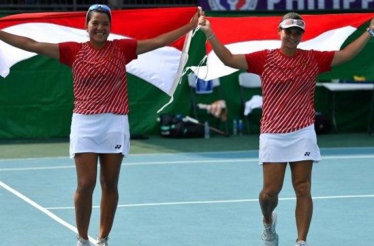 Petenis Indonesia, Jessy Rompies (kiri) dan Beatrice Gumulya mengibarkan bendera Merah-Putih sesuai mengalahkan petenis Thailand Peangtarn Plipuech dan Tamarine Tanasugarn dalam final ganda putri SEA Games 2019 di lapangan Rizal Memorial Tennis Center, Manila, Filipina, Sabtu (7/12). [Antara/Sigid Kurniawan]