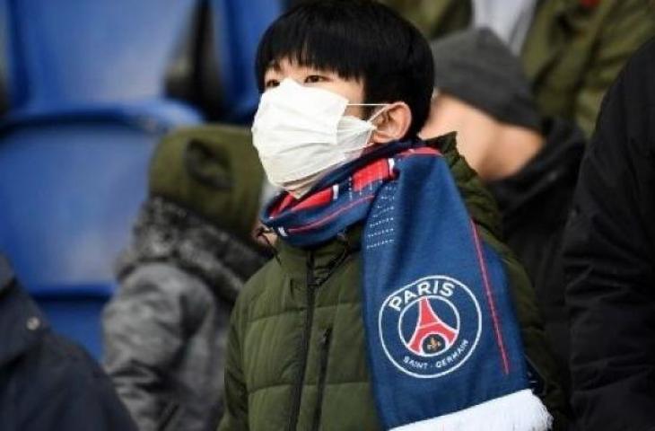 Suporter Paris Saint-Germain (PSG) memakai masker meyusul merebaknya virus corona saat menyaksikan laga melawan Dijon pada laga lanjutan Ligue 1 di Parc des Princes stadium, Paris. (FRANCK FIFE / AFP)