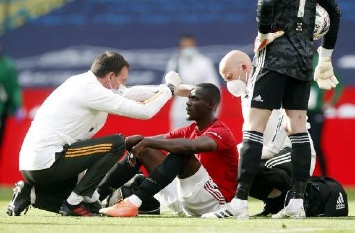 Bek Manchester United, Eric Bailly saat mendapat perawatan dari tim medis usai cedera parah di bagian kepalanya. (ANDY RAIN / POOL / AFP)