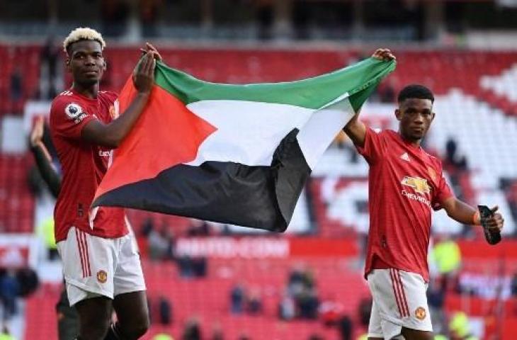 Paul Pogba dan Amad Diallo kibarkan bendera Palestina. (Laurence Griffiths / POOL / AFP)