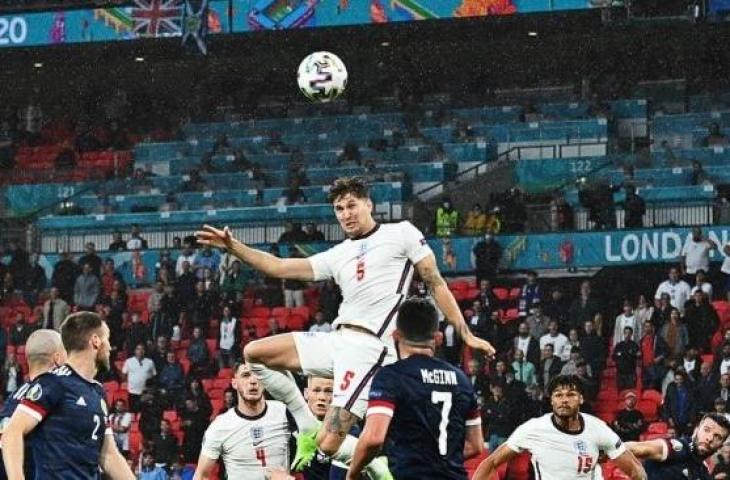 Bek Timnas Inggris, John Stones (nomor 5) melompat untuk menanduk bola saat menghadapi Skotlandia dalam matchday kedua Grup D Euro 2020 di Stadion Wembley, London, Sabtu (18/6/2021) dini hari WIB. [JUSTIN TALLIS / POOL / AFP].