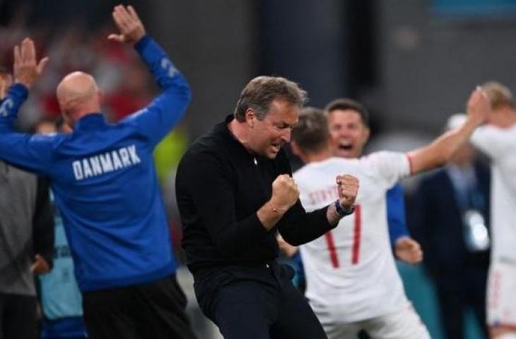 Pelatih Denmark Kasper Hjulmand bersama para staf dan pemain merayakan kepastian timnya lolos 16 besar Euro 2020 usai menang 4-1 atas Rusia, Selasa (22/6/2021) dini hari WIB. (Foto: Stuart FRANKLIN/AFP)