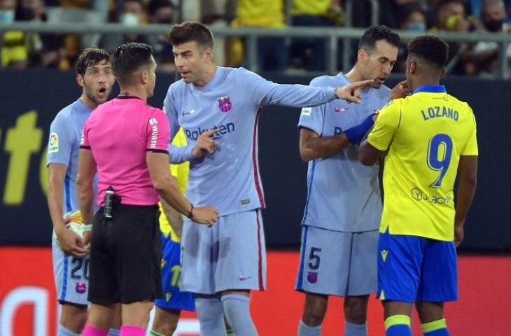 Pemain Barcelona, Gerard Pique protes ke wasit usai Frankie de Jong diganjar kartu merah saat laga melawan Cadiz, Kami (23/9/2021). (AFP/Cristina Quicler)