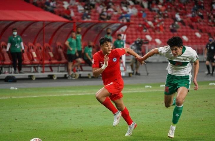 Striker Timnas Singapura, Ikhsan Fandi berebut bola dengan bek Timnas Indonesia Elkan Baggott di leg pertama semifinal Piala AFF 2020, Rabu (22/12/2201). (dok.AFF Suzuki Cup)