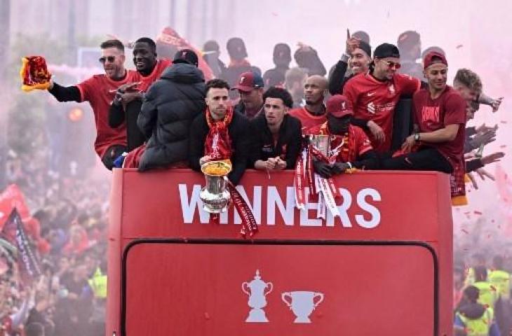 Para pemain Liverpool melambaikan tangan kepada para suporter dari bus terbuka selama parade melalui jalan-jalan Liverpool, Inggris pada 29 Mei 2022, untuk merayakan kemenangan Piala Liga dan Piala FA 2021-22. (AFP)