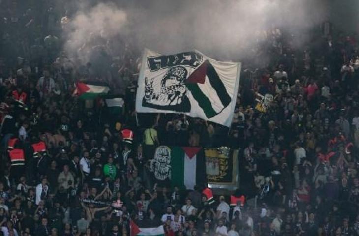 Suporter PSG bentangkan bendera Palestina saat Les Parisiens jumpa klub Israel di Liga Champions. (Geoffroy VAN DER HASSELT / AFP)