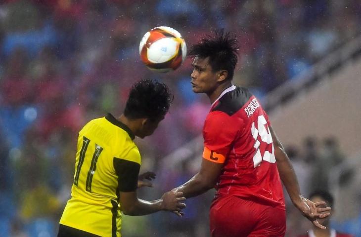 Pemain Malaysia Muhammad Syafik bin Ismail (kiri) bertarung memperebutkan bola dengan pemain Indonesia Fachruddin Wahyudi Aryanto dalam pertandingan memperebutkan medali perunggu SEA Games di Hanoi pada 22 Mei 2022. (Ye Aung Thu/AFP)