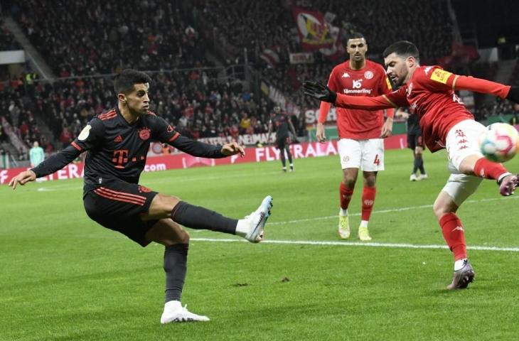 Bek Mainz Aaron Martin (kanan) dan bek Bayern Munich Joao Cancelo berebut bola selama pertandingan 16 besar Piala Jerman (DFB Pokal) di Mainz, barat daya Jerman pada 1 Februari, 2023. (AFP/Thomas Kienzle)