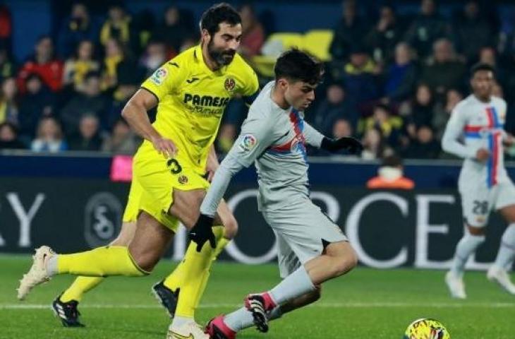 Gelandang Barcelona Pedri (kanan) menendang bola untuk mencetak gol pertama timnya selama pertandingan pekan ke-21 Liga Spanyol saat melawan Villarreal di Stadion La Ceramica. (JOSE JORDAN / AFP)