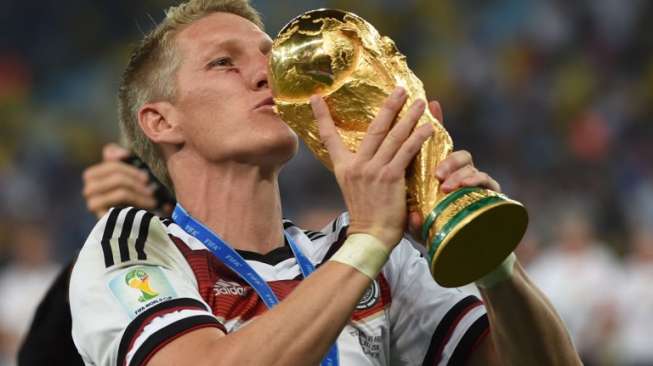 Bastian Schweinsteiger mencium trofi Piala Dunia 2014 usai mengalahkan Argentina di partai final. [AFP]