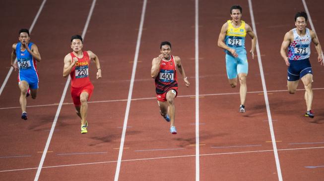 Pelari Indonesia Lalu Muhammad Zohri (tengah) berlari memacu langkahnya ke garis finis pada kualifikasi nomor lari 100 m putra grup C Asian Games 2018 di Stadion Gelora Bung Karno, Senayan, Jakarta, Sabtu (25/8). [Antara/INASGOC/M Agung Rajasa]