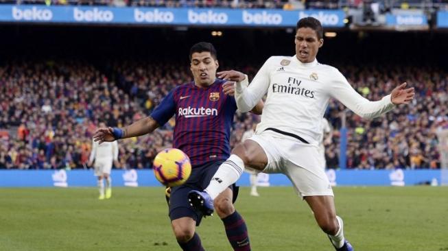 Penyerang Barcelona Luis Suarez (kiri) berebut bola dengan Real Madrid Raphael Varane saat laga di Camp Nou di La Liga. Josep LAGO / AFP