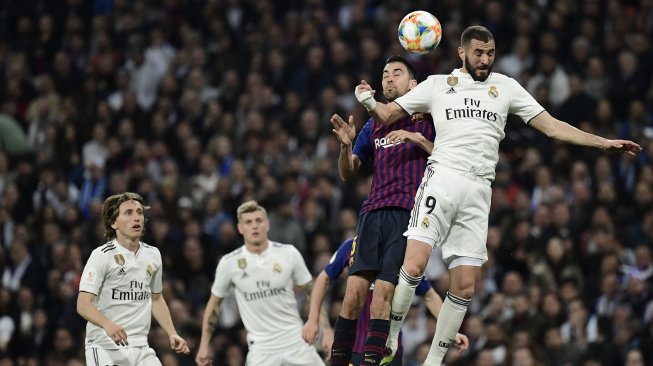 Pemain depan Real Madrid Karim Benzema bersaing dengan pemain tengah Barcelona Sergio Busquets selama pertandingan sepak bola leg kedua semifinal Copa del Rey Spanyol antara Real Madrid melawan Barcelona di Stadion Santiago Bernabeu, Madrid, Spanyol, Kamis (28/2) dini hari WIB. [JAVIER SORIANO / AFP]