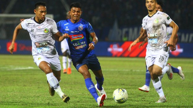 Pesepak bola Arema FC, Dedi Setiawan (tengah) berusaha melewati hadangan pesepak bola PS Tira, Andy Setyo Nugroho (kiri) dan Khurshed Beknazarov (kanan) dalam pertandingan Liga I di Stadion Gajayana, Malang, Jawa Timur, Sabtu (29/6/2019). ANTARA FOTO/Ari Bowo Sucipto