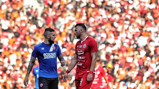 Pesepak bola Persija Jakarta Simic duel dengan pesepak bola PSM Makassar Aaron Michael Evans dalam pertandingan Final Piala Indonesia 2018-2019 leg pertama di Stadion Utama Gelora Bung Karno (GBK), Senayan, Jakarta, Minggu (21/7). [Suara.com/Muhaimin A Untung]