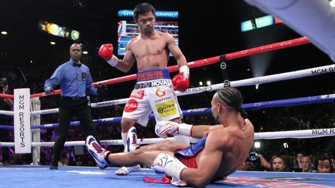 Petinju Keith Thurman (kanan) terjatuh di kanvas usai dipukul penantangnya, Manny Pacquiao (tengah), dalam duel di MGM Grand Garden Arena, Las Vegas, AS, Sabtu (20/7/2019). [AFP/John Gurzinski]