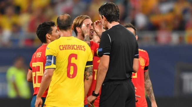 Kapen Timnas Spanyol, Sergio Ramos (tengah) mencoba menjelaskan selebrasi yang dia lakukan kepada wasit pada kualifikasi Piala Eropa 2020 antara Rumania vs Spanyol di Stadion Arena Nationala, Rumania, Jumat (6/9/2019). (Daniel MIHAILESCU / AFP)