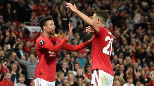 Penyerang belia Manchester United, Mason Greenwood (kiri) merayakan golnya ke gawang Astana bersama fullback Diogo Dalot, dalam laga Liga Champions 2019/2020 di Old Trafford, Manchester, Jumat (20/9/2019) dini hari WIB. [Oli SCARFF / AFP]