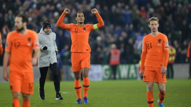 Bek Timnas Belanda, Virgil van Dijk merayakan keberhasilan timnya lolos ke Piala Eropa 2020 meski bermain imbang 0-0 tanpa gol menghadapi Irlandia Utara, Minggu (17/11/2019). [MARK MARLOW / AFP]