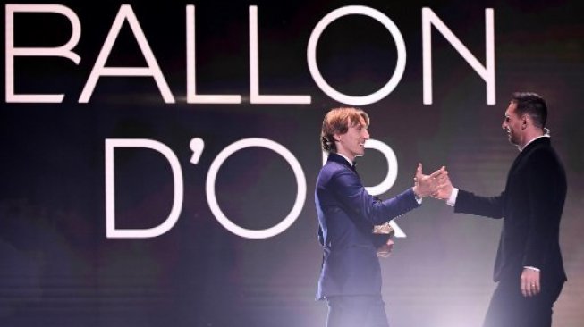 Gelandang Real Madrid dan peraih Ballon d'Or Luka Modric (kiri) memberikan trofi Ballon d,Or kepada Lionel Messi dalam acara seremoni di Chatelet Theatre, Paris. FRANCK FIFE / AFP