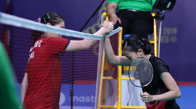 Pebulutangkis tunggal putri Indonesia, Fitriani (kanan) bersalaman dengan lawannya Busanan Ongbamrungphan dari Thailand usai kalah dalam pertandingan beregu putri SEA Games 2019, Selasa (3/12). [Humas PBSI]