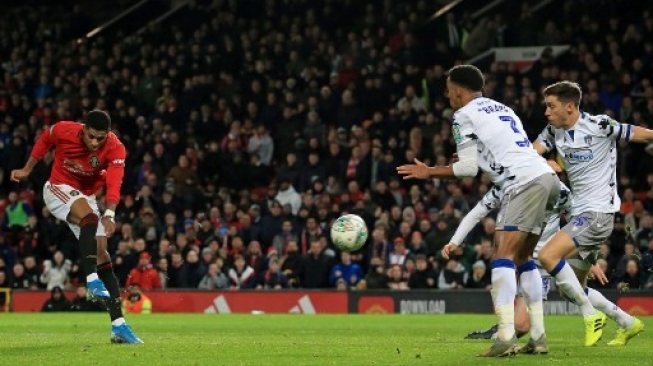 Striker Manchester United Marcus Rashford (kiri) melepaskan sepakan kerasnya guna mencetak gol ke gawang Colchester United di perempat final Piala Liga Inggris di Old Trafford. Lindsey Parnaby / AFP