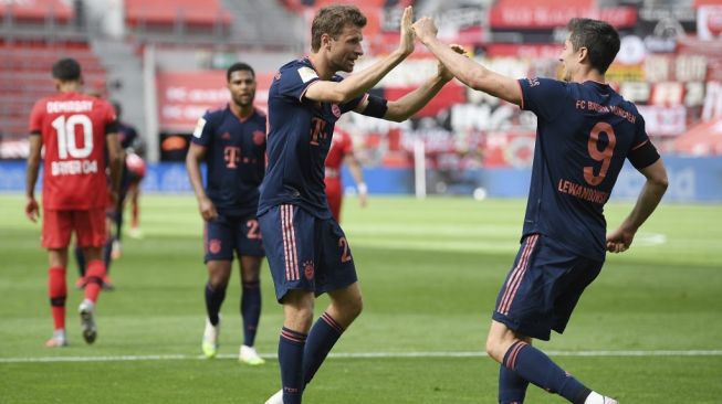 Penyerang Bayern Munich, Robert Lewandowski (kanan) dan gelandang serang Thomas Muller merayakan gol pada laga lanjutan Bundesliga 2019/2020 kontra tuan rumah Bayer Leverkusen, Sabtu (6/6/2020) malam WIB. [Matthias Hangst / POOL / AFP]