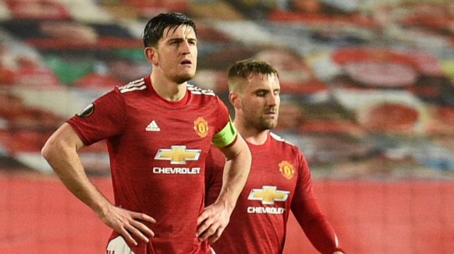 Kapten Manchester United, Harry Maguire (kiri) dan Luke Shaw tampak kecewa setelah timnya kebobolan di menit-menit akhir pertandingan saat menghadapi AC Milan dalam pertandingan leg pertama babak 16 besar Liga Champions di Old Trafford, Jumat (12/3/2021) dini hari WIB. [Oli SCARFF / AFP].