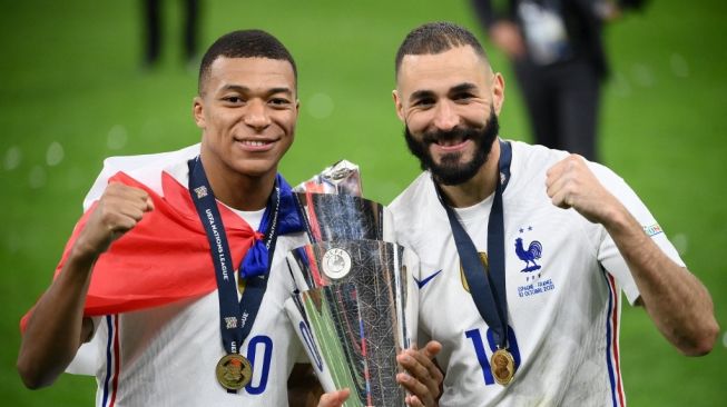 Penyerang timnas Prancis Kylian Mbappe (kiri) dan Karim Benzema (kanan) merayakan gelar juara UEFA Nations League dengan memegang trofi di akhir pertandingan final UEFA Nations League antara Spanyol vs Prancis di stadion San Siro di Milan, pada 10 Oktober 2021.FRANCK FIFE / AFP.