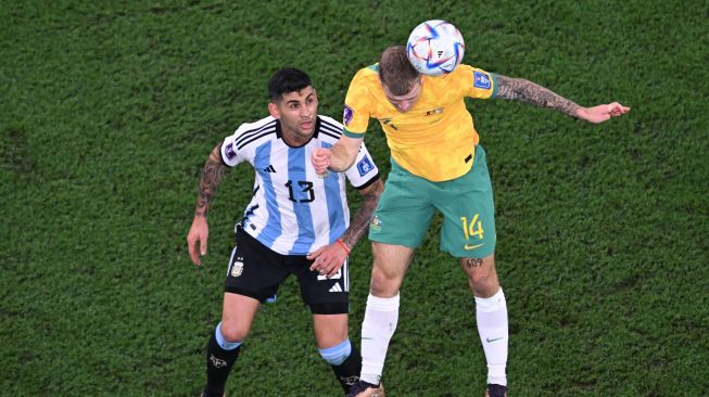 Gelandang Australia Riley McGree menyundul bola di depan bek Argentina Cristian Romero saat pertandingan sepak bola babak 16 besar Piala Dunia 2022 antara Argentina dan Australia di Stadion Ahmad Bin Ali di Al-Rayyan, barat Doha, Qatar, Sabtu (3/12/2022). [Kirill KUDRYAVTSEV / AFP]