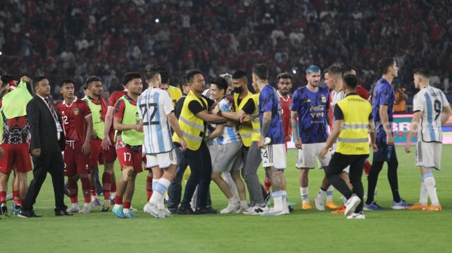 Seorang suporter mengenakan jersey Timnas Indonesia dan Argentina diamankan usai masuk ke dalam lapangan Stadion Utama Gelora Bung Karno (SUGBK), Senayan, Jakarta, Senin (19/6/2023). [Suara.com/Dwi Bowo Raharjo]